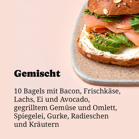 Gemischte Bagel-Box zum Abholen bei Café Adeli Köln: Vollkorn-Bagel reichhaltig belegt mit Räucherlachs, Frischkäse, Avocado und frischen Kräutern auf Keramikteller