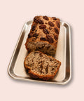 Veganes Bananenbrot von Adeli mit Schoko und Pekannüssen, aufgeschnitten auf einem Backblech, ca. 30 cm