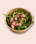 Veganer gemischter Salat von Adeli mit Gurkennudeln, Radieschen und gerösteten Kernen in einer Schüssel